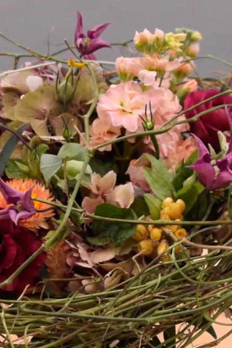 cesta primaveral con flores naranjas y rosadas